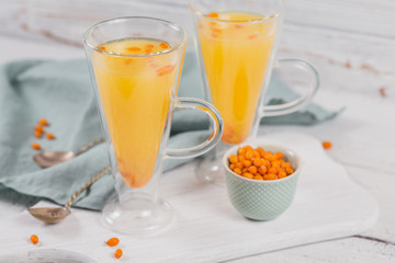 Two high glasses with colorful hot sea buckthorn tea with fresh sea buckthorn berries