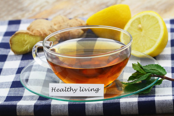 Healthy living card with cup of tea, fresh mint leaves, fresh ginger and juicy lemon
