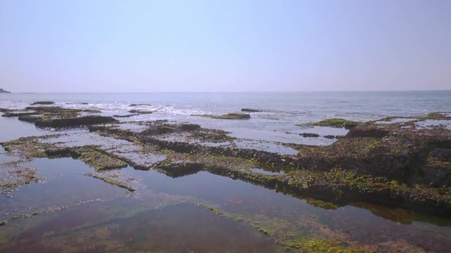 Waves dashing against the moss covered rocks on a beach in Diu, Gujarat, India