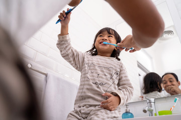 kid and dad having fun while brushing their teeth