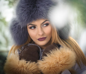 Attractive woman with brown fur cap and jacket enjoying the winter. Side view of fashionable blonde...
