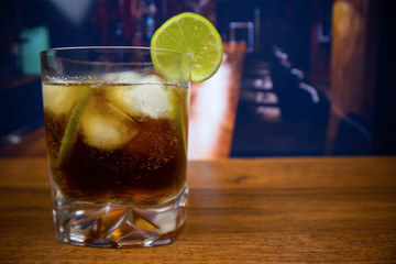 Rum cola cocktail in old fashioned glass with ice and lime