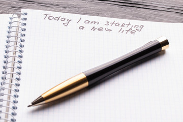 Top view workplace notebook and pen on wood table background. Inscription - Today I am starting a new life.