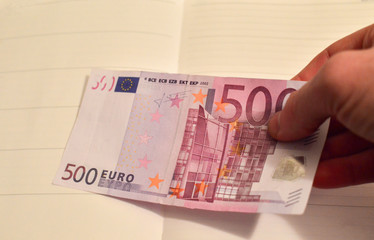Man's hand holding a big money bill, 500 euros in one hand. The bill of 500 euros out of circulation