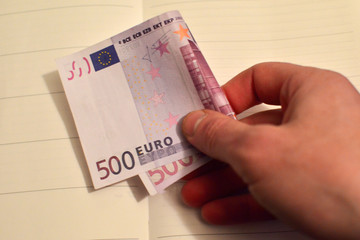 Man's hand holding a big money bill, 500 euros in one hand. The bill of 500 euros out of circulation