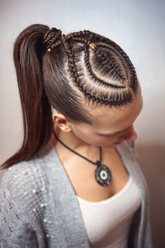 cornrows hairstyle for a girl with dark hair, thin braids tied in a tail