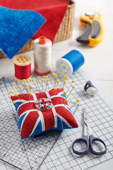 Fototapeta na wymiar Pincushion like Union Jack on white craft mat, sewing accessories