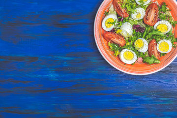 Salad with lettuce, eggs, tomatoes and sesame in orange plate