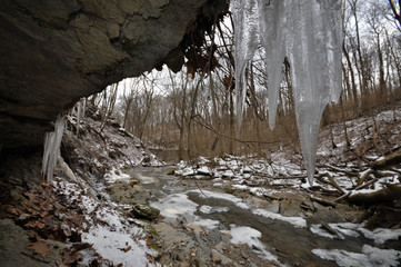 Fototapeta na wymiar Icicles and frozen stream in the forest in winter