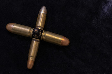 Pistol bullets gathered together in the shape of a cross. War concept. Dark background shot.