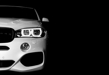 Headlight of a modern white sport car. The front lights of the car. Modern Car exterior details. Car detailing. Isolated on black background. Car detailing