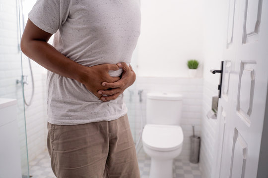man hold his stomach painful in the toilet
