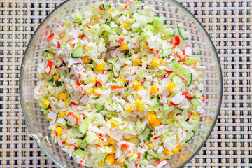 Salad with corn and crabs in a round glass bowl