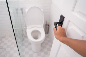 hand opening the toilet door