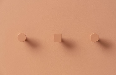 Metal orange hangers in forms of circle and square and hexagon on colorful wall in studio