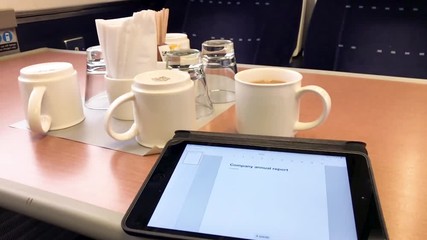 Writing a company annual report on a computer tablet, in a British first class train carriage.