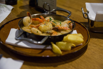 Shrimp delicious stew served in small pan. shrimps in cream sauce dish in a restaurant. Tapas style seafood healthy dish.