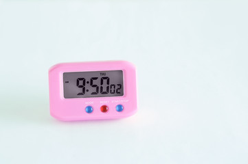 Pink electronic clock on a white background. Close-up.