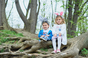 Naklejka na ściany i meble Cute funny girl and boy with Easter eggs at park. easter concept. Children playing with easter eggs on Easter day.
