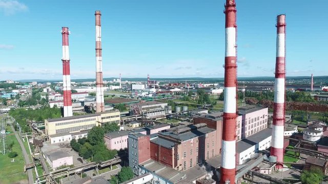 Aerial view of industrial plant with red and white striped chimneys near the road. Footage. Industrial zone from above