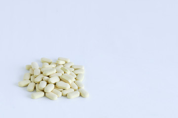 Beige pills loose in a pile. On a white background.