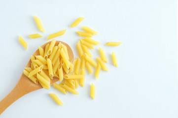 Pasta noodles on a wooden spoon and scattering. White background.