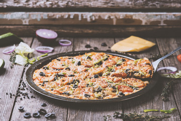 Freshly baked pizza in pizza mold and on wooden table. Matte effect