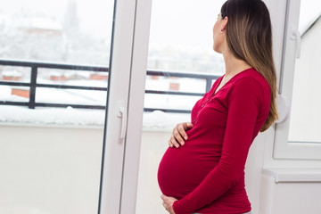 Pregnant woman standing next to window