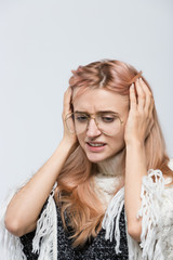 Fototapeta premium Cropped indoor portrait of attractive panicked girl with stylish eyewear holding her head, doesn't know what to do, looking at the floor/confused young female/human emotions, facial expression concept