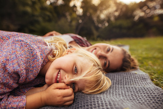 Little girl lying on picnic plaid with mother at back