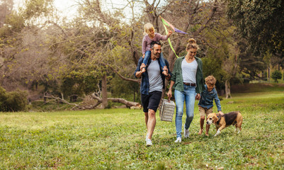 Family with dog going on picnic in park - obrazy, fototapety, plakaty