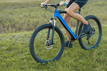 Fototapeta premium A girl riding a mountain bike on an asphalt road, beautiful portrait of a cyclist at sunset 