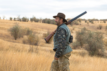 Hunter with a hat and a gun in search of prey in the steppe	