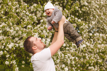 Baby with faher in the park in the rays of sunset. Toddler on the nature outdoors. Backlight. Summertime family  scene