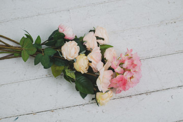 Tender light roses on white wooden background