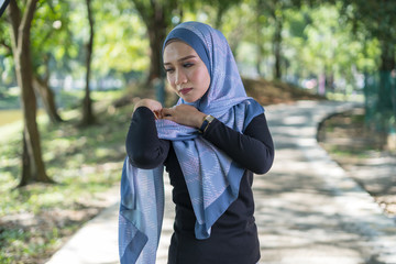 Happy face, young Asian woman with tudung or hijab smile and standing at green park.