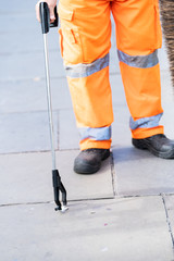 Man worker cleaner in orange uniform cleaning trash rubbish streets in London with picker tool on...