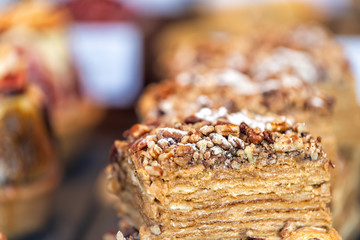 Closeup macro view of layered tart cake slice desserts on trays in gourmet bakery cafe pastries with detail and texture, nuts and powdered sugar