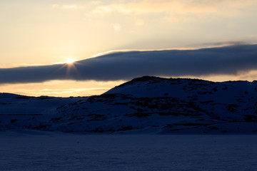 Winter time, snow shore, Russia, landscape of beautiful wild nature of north sees. Beautiful snow winter ice and cold landscape, picturesque view with mountains on horizon, sky clouds, sun lens flare