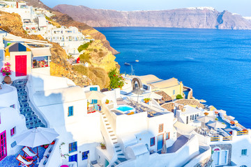 Famous European Destinations. Breathtaking View of Classic White Roofed Houses and Pastel-Blue Colors of Oia Village on Santorini Island in Greece With Boats in Background.