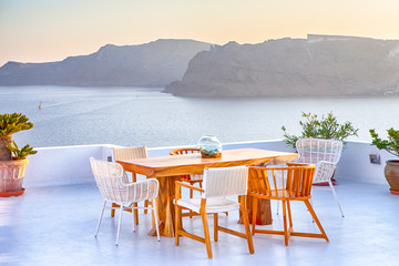 Tranquil and Romantic Atmosphere at Open Air Terrace Restaurant in Beautiful Oia Village on Santorini Island in Greece in Front of Volcanic Caldera Mountain.