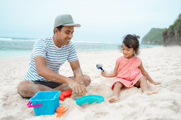father with daughter playing sand castle