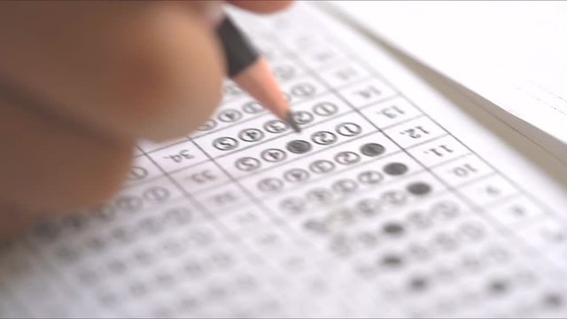 Test exam concept, pencil writing answer on paper answer of question in examination test.