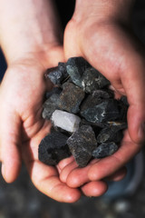A close up coal rocks being held in a hand.
