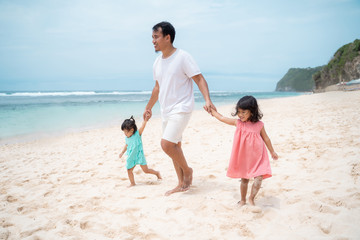 father and two daughter walking around the beach