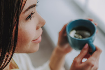 Profile of young lady tasting hot tea with lemon