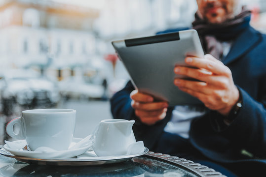 Man is using tablet and drinking coffee in cafe