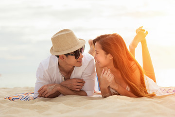 Asian couple lying Honeymoon at sunset tropical beach