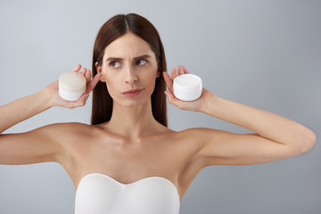 Beautiful young lady in white bra holding cosmetic products