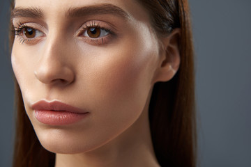 Obraz premium Beautiful girl with natural makeup standing against blue-gray background